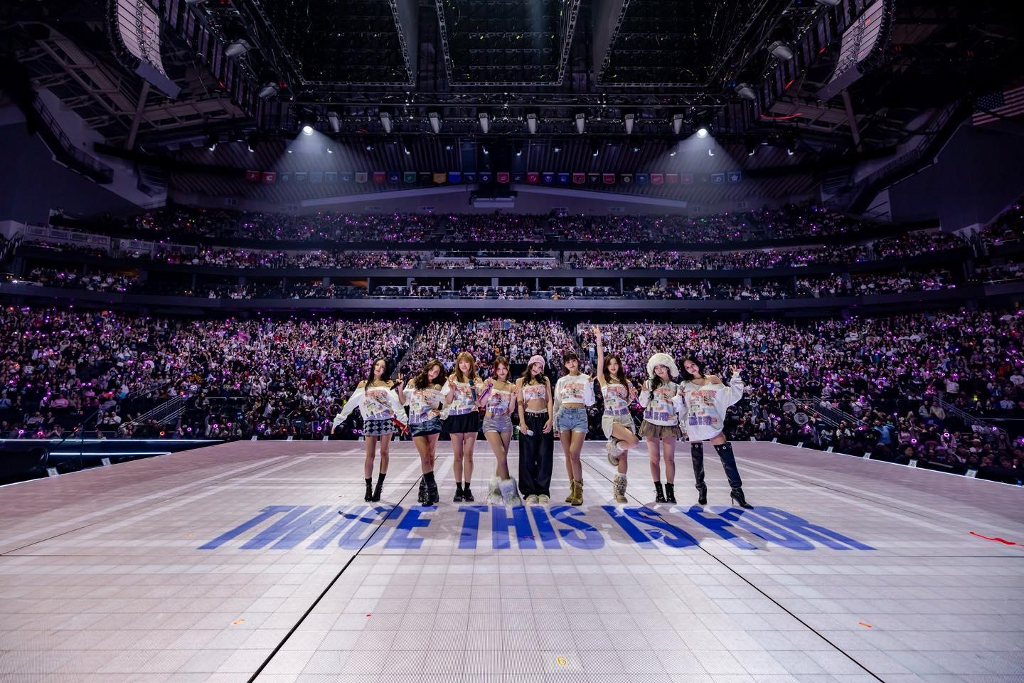 فرقة TWICE خلال حفل مباشر في مدينة سانت بول الأمريكية وسط جمهور كبير وأضواء مسرحية مبهرة