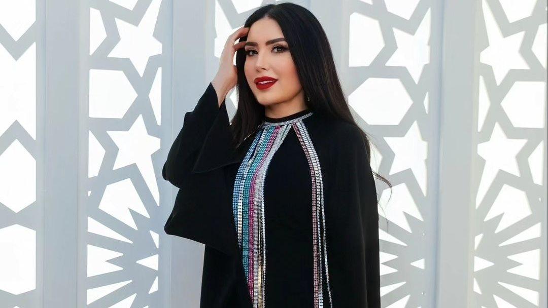عبير صبري بإطلالة أنيقة باللون البني الداكن، فستان طويل، أكسسوارات ذهبية، وحذاء بكعب عالٍ.