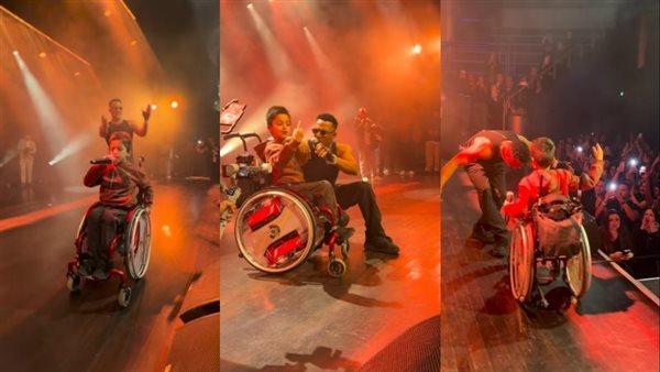 محمد رمضان يغني مع طفل عراقي على كرسي متحرك خلال حفل هولندا، مع جمهور متفاعل