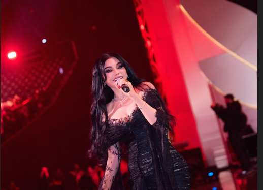 هيفاء وهبي بإطلالة دانتيل أسود مكشوف الأكتاف في حفل موسم الرياض، مع شعر كيرلي طويل ومكياج ناعم.