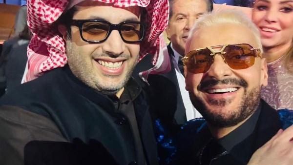 رامز جلال مع تركي آل الشيخ في حفل Joy Awards، مرتديًا بدلة زرقاء وقناعًا أبيض.
