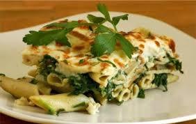 طبق مكرونة بالجبن والسبانخ على طبق أبيض مع رشة جبن مبشور