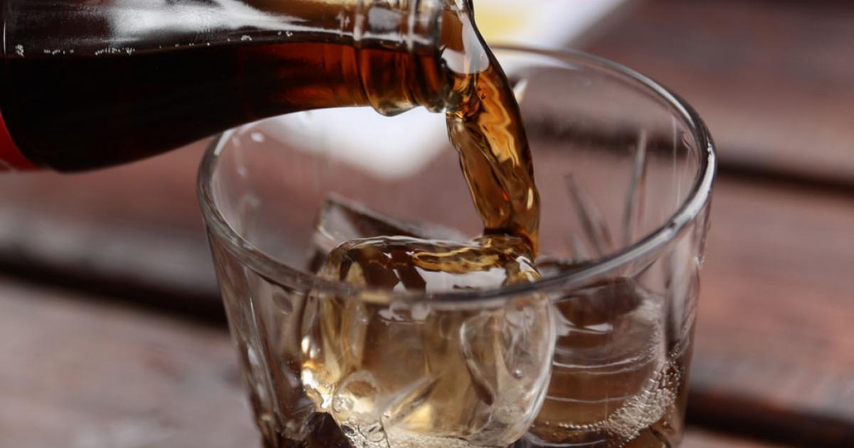 شخص يحمل عبوة مشروب دايت مع تحذير حول المخاطر الصحية