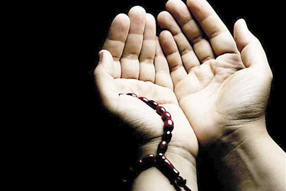 رجل يرفع يديه بالدعاء وسط نورٍ يتسلل من بين الغيوم بعد المطر